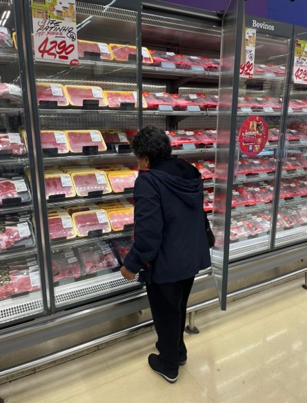 Senhora escolhendo carne embalada na gôndola